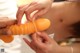 A woman is holding a large orange dildo in her hands.