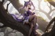 A woman in a purple dress sitting on a tree branch.