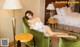 A woman sitting in a green chair in a hotel room.