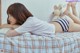 A woman laying on a bed with a teddy bear.