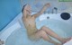 A naked woman is sitting in a bathtub with water.