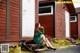 A woman in a green dress sitting on the steps of a house.