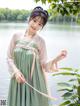 a woman in a green dress standing next to a body of water